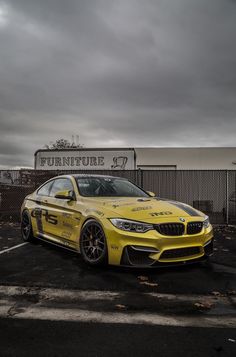 a yellow bmw car parked in front of a furniture store sign on a cloudy day