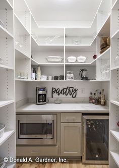 a kitchen with lots of white shelves and silver appliances