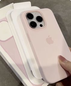 a person holding an iphone case in front of three other cases, one pink and the other white