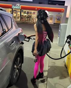 a woman is pumping gas into her car