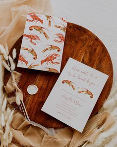 the wedding stationery is laid out on a round wooden tray with feathers and flowers