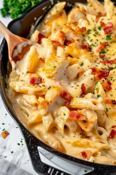 a skillet filled with macaroni and cheese covered in bacon, parsley