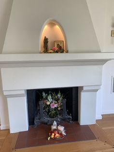 a fireplace with flowers on the mantle and an angel figurine in the corner