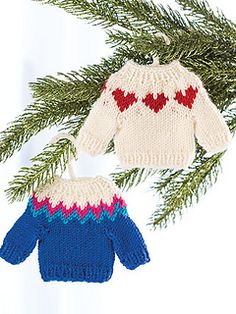 two knitted sweaters hanging from a christmas tree ornament on a white background