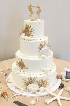 there is a wedding cake with sea shells on the table