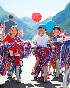 three children riding bikes with american flags on them and balloons in the air behind them