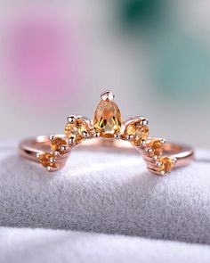 a yellow diamond ring sitting on top of a white cloth