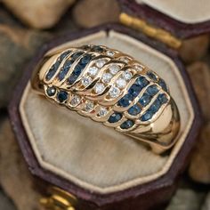 This diamond and sapphire ring features channel set diamonds and blue sapphires in a wave motif. The ring is low-profile and is crafted in 14k yellow gold. It is currently a size 6.25. The sapphires have some very light amount of abrasion that cannot be seen with the unaided eye. Luxury Gold Sapphire Ring In Recycled Gold, Luxury Gold Sapphire Fusion Ring, Sapphire Eternity Ring, Channel Set, Sapphire Jewelry, Sapphire Ring, Blue Sapphire, Sapphire, Jewelry Rings