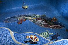 an artistic mosaic in the shape of a fish and sea life is featured on the floor