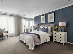 a bedroom with blue walls and carpeted flooring has a large bed in it