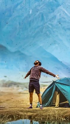 a man standing in front of a tent next to a body of water with birds flying over it