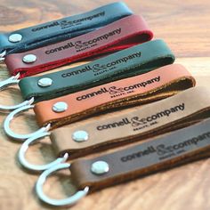 four different colored leather key chains on top of a wooden table