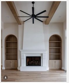 an empty living room with a fireplace and bookcases