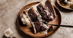 a piece of chocolate cake on a plate with a fork and marshmallows