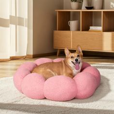 a small dog laying on top of a pink cloud shaped bed in a living room