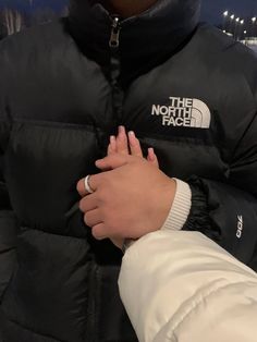 a person wearing a black jacket with the north face logo on it's chest