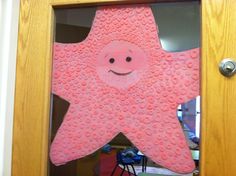 a pink starfish door hanger with a smiley face on it's side