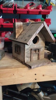 a wooden birdhouse sitting on top of a table next to tools and other items