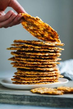 a stack of crackers on a plate being held up by a person's hand