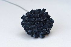 a close up of a black flower on a white surface with a cord attached to it