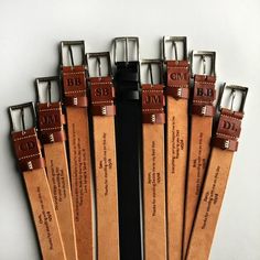 six pairs of leather belt straps with engraved names on each one side and the other end