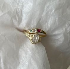 two rings with different colored stones sitting on top of a white cloth covered tablecloth