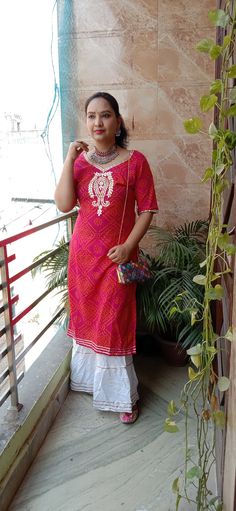 a woman standing on a porch next to a plant