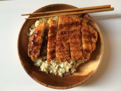 a plate with rice, meat and chopsticks on it