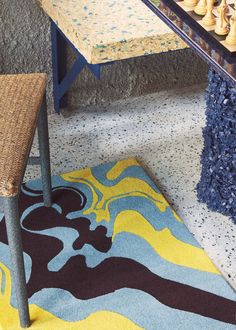 a table with chess pieces on it in front of a rug and chair next to the table