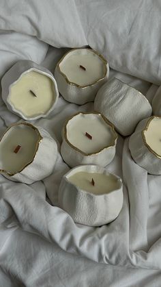 six white candles sitting on top of a bed