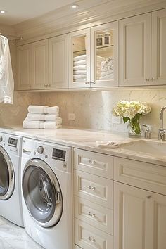 a washer and dryer in a very clean room with white cabinets on the walls