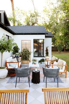 an outdoor patio with chairs, tables and potted plants in front of the house