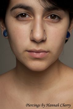 a woman with piercings on her nose and nose ring in front of her face