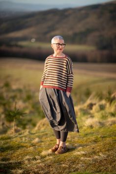 an older woman standing on top of a lush green hillside