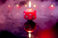 a red dice sitting on top of a table next to a lit candle with numbers