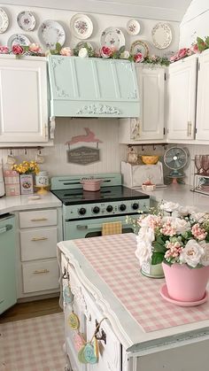 a pink and white kitchen with lots of plates hanging on the wall above the stove