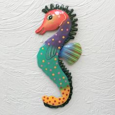 a colorful seahorse is hanging on the wall in front of a white painted wall