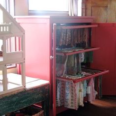 a red cabinet filled with clothes next to a window