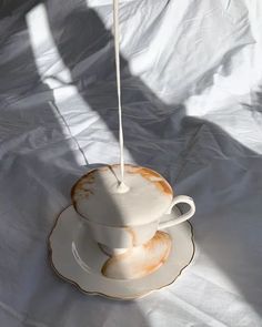 a tea cup and saucer sitting on top of a white sheet