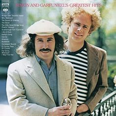 two men standing next to each other in front of a white fence with the words simon and garfunkes greatest hits on it