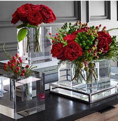 three clear vases with red flowers in them