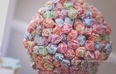 a purple vase filled with lots of candy on top of a table next to a wall