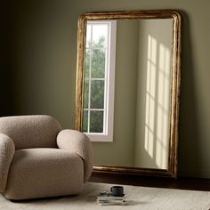 a chair sitting in front of a large mirror on top of a floor next to a window