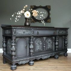 an ornately decorated sideboard with flowers in a vase sitting on top of it