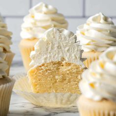 cupcakes with white frosting and one half eaten