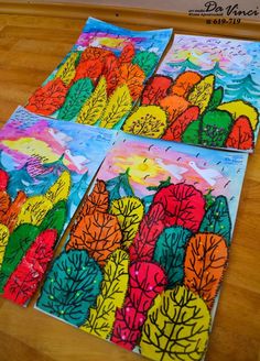 four colorful cards with trees on them sitting on a wooden table next to each other