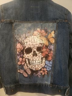 a jean jacket with a skull and flowers on it