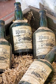 several old wine bottles are sitting in the straw on the ground next to each other