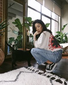 a woman sitting on the floor next to a black cat