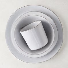 a white cup and saucer sitting on top of each other in front of a plate